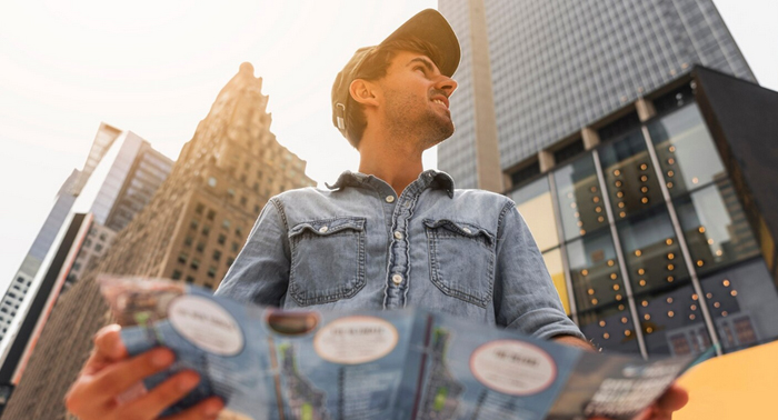 Young man holding a map in a cityscape, exploring Los Angeles, reflecting themes of financial navigation and planning related to payday loans.