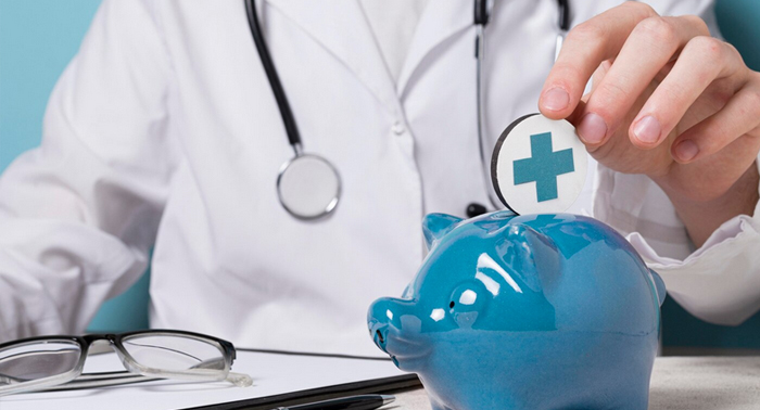 Doctor placing a coin with a medical cross symbol into a blue piggy bank, representing financial health and emergency payday loans.